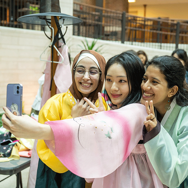 Three female students take a selfie while holding up their fingers in a peace sign