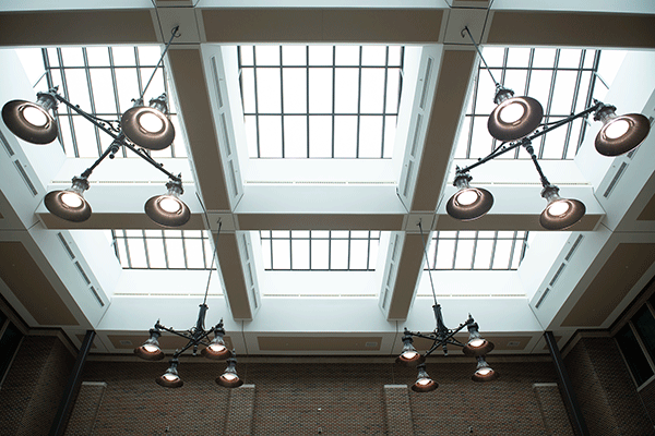 Large circular lamps and large windows that make up the ceiling in the atrium of the Bayh College of Education.